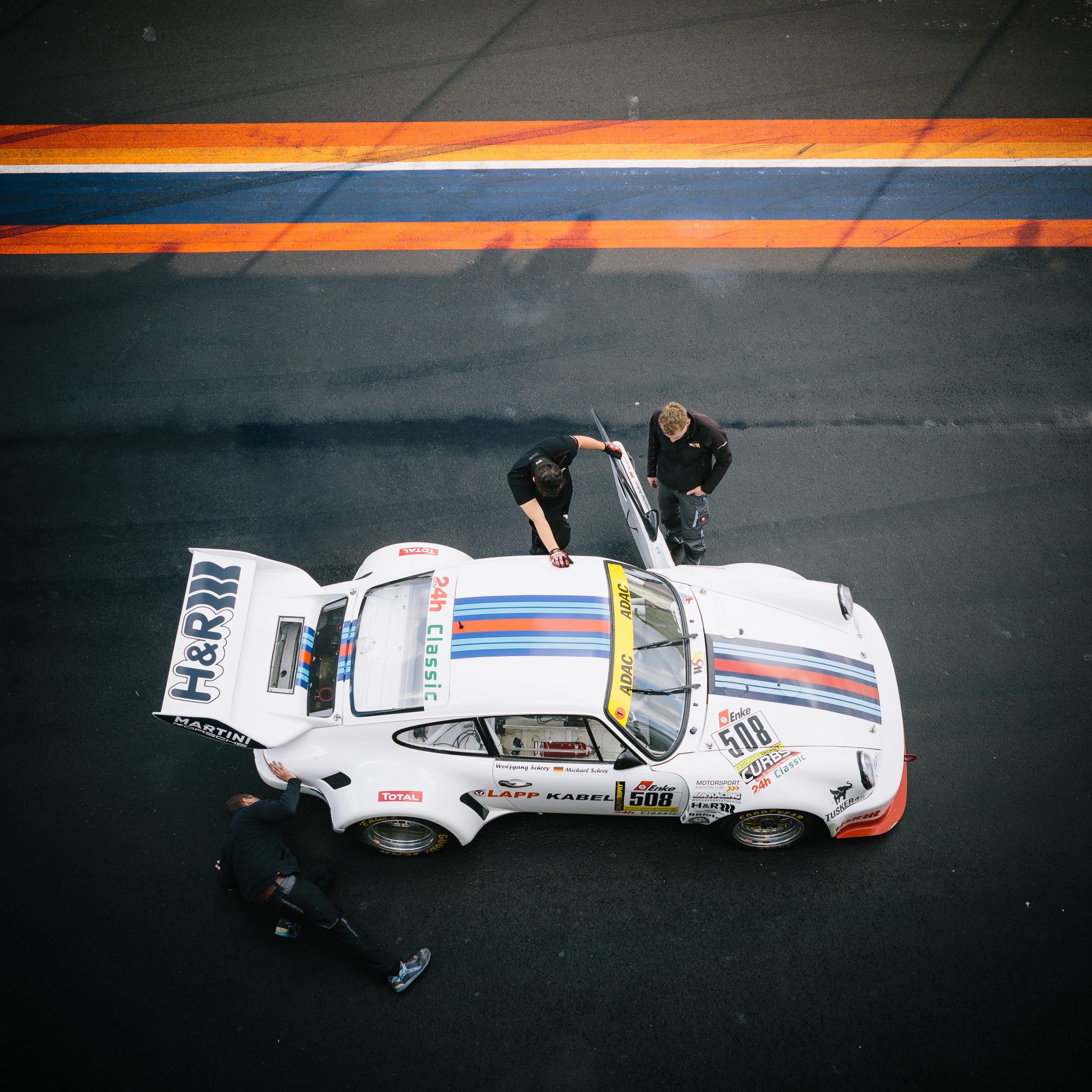 classic white Porsche 911 at pit stop with crew